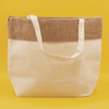 A jute and cotton cooler bag in cream with a brown jute top and white straps, featuring a logo.