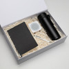 A black drink bottle, a notebook, a white speaker, and a pen packed in a gift box with shredded paper.