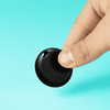 A circular black tracking device held between fingers, set against a bright turquoise background.