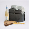 A drink bottle, picnic blanket, wooden cutting board with knife, and a grey cooler bag. The drink bottle is white.