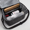 A drink bottle cooler bag in grey containing a bottle of wine, a rolling pin, and a rolled-up blanket.
