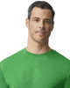 A green Gildan performance adult T-shirt displayed on a model with a neutral expression. The shirt features a logo.