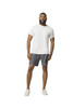 A man wearing a white Gildan Performance adult T-shirt and grey shorts, standing casually and smiling.
