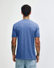 A blue American Apparel tri-blend T-shirt seen from the back, worn by a person with tattoos.