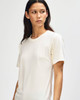 A light cream American Apparel Tri-Blend T-shirt on a model, featuring a relaxed fit and subtle branding.