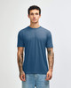 A blue American Apparel tri-blend T-shirt displayed on a model with tattoos, paired with denim jeans.