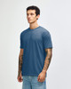 A blue tri-blend t-shirt displayed on a model with tattoos, featuring a simple design and no visible logos.
