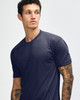 A navy blue tri-blend T-shirt displayed on a model with tattoos, featuring a simple design and a logo.