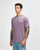 A man wears a purple American Apparel tri-blend t-shirt paired with light denim jeans. The shirt has a casual fit.