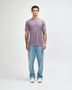 A model wearing a lavender American Apparel Tri-Blend T-Shirt paired with light blue jeans and white sneakers.