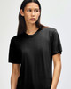 A black American Apparel Tri-Blend T-shirt displayed on a model with long hair. The shirt has a relaxed fit and a logo.