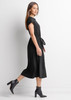 A black midi dress with short sleeves and a tied waist, featuring a model walking in profile.