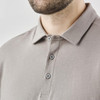 A men's long-sleeve polo shirt in a muted grey shade featuring a collar and button details. It includes a logo on the chest.