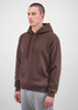 A brown hoodie with a front pocket and drawstring hood, modelled by a man wearing grey sweatpants.