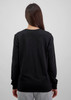 A black long sleeve women's tee, showing the back view and paired with light grey pants. The shirt has a logo.