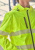 A bright yellow unisex packable rain jacket featuring reflective strips and a hood, with a black zip and pocket.