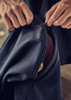 A close-up of hands zipping a navy softshell jacket with a contrasting inner layer. The jacket features a logo.