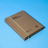 A brown A5 notepad secured with a rubber band, featuring a logo on the cover against a blue background.