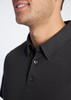 A close-up of a black men's polo shirt featuring a collar and buttons, with a branding logo present.