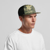 A camo trucker cap featuring a mix of green and black tones, with a mesh back and a logo.