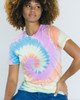 A woman models a Colortone® tie dye adult T-shirt featuring a spiral pattern in pastel colours of blue, pink, yellow, and green.
