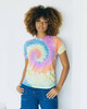 A tie-dye adult t-shirt in pastel colours, featuring a spiral design. A model poses while leaning against a wall.