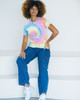 A tie-dye adult T-shirt in pastel colours, featuring a spiral pattern, worn with casual blue jeans and white sneakers.