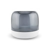 A rounded speaker with a smoke grey top and a white base, featuring a modern design and smooth surface.