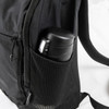 A black daypack features a side mesh pocket holding a black drink bottle. The bag has zippers and adjustable straps.