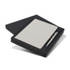 A grey notebook and a silver pen presented in a black gift box. The box is slightly opened to reveal the contents.