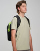 A backpack in black with lime green accents is worn on one shoulder by a young man in a light grey shirt.