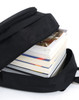 A black backpack partially open, revealing several stacked books inside. The backpack features a zip closure and a simple design.