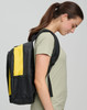 A black and yellow backpack worn by a woman, displayed from the side against a neutral background.