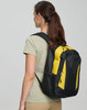 A black and yellow backpack is worn on the back of a person facing away from the camera. The backpack has a logo.