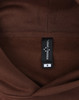 A brown unisex oversized hoodie with a tag displaying size information and a logo.