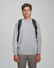 A model wearing a grey long-sleeve shirt and khaki pants, showcasing a black backpack on both shoulders.