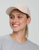 A beige Jacquard Texture 5 Panel Cap worn by a smiling individual, featuring a logo on the front.