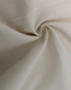 A close-up of a light beige cotton blend fabric, showcasing its soft texture and woven pattern.