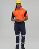 A man wearing a high-visibility orange polo shirt and navy work pants with reflective tape, along with a yellow hard hat.