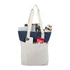 A white and navy tote bag with a drink bottle, phone, magazines, and a snack pack visible inside.