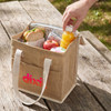 A cooler bag in natural tones containing a sandwich, apple, juice bottle, and a napkin, with an outer logo.