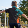 A boy wearing a black, teal, and orange custom youth active polo shirt in an outdoor playground setting.