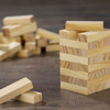 A set of small wooden blocks in light wood tones, stacked to form a tower, with additional blocks scattered nearby.