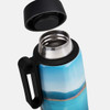 A drink bottle with a blue and scenic design, featuring a black handle and a stainless steel opening.