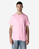 A pink Gildan Light Cotton T-Shirt displayed on a model wearing blue jeans. The shirt has a simple design and includes a logo.