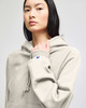 A light grey hooded sweatshirt featuring a kangaroo pocket and a logo on the sleeve.