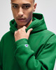 A green hooded sweatshirt with a logo, featuring a relaxed fit and front pocket. Perfect for casual wear.