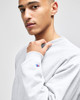 A grey Champion Reverse Weave® adult crew sweatshirt with a logo on the sleeve, modelled by a young man.