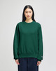 A green Champion Reverse Weave® adult crew sweatshirt displayed on a model, featuring a logo on the sleeve.