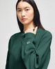A model wearing a dark green Champion Reverse Weave® adult crew sweatshirt featuring a logo on the sleeve.